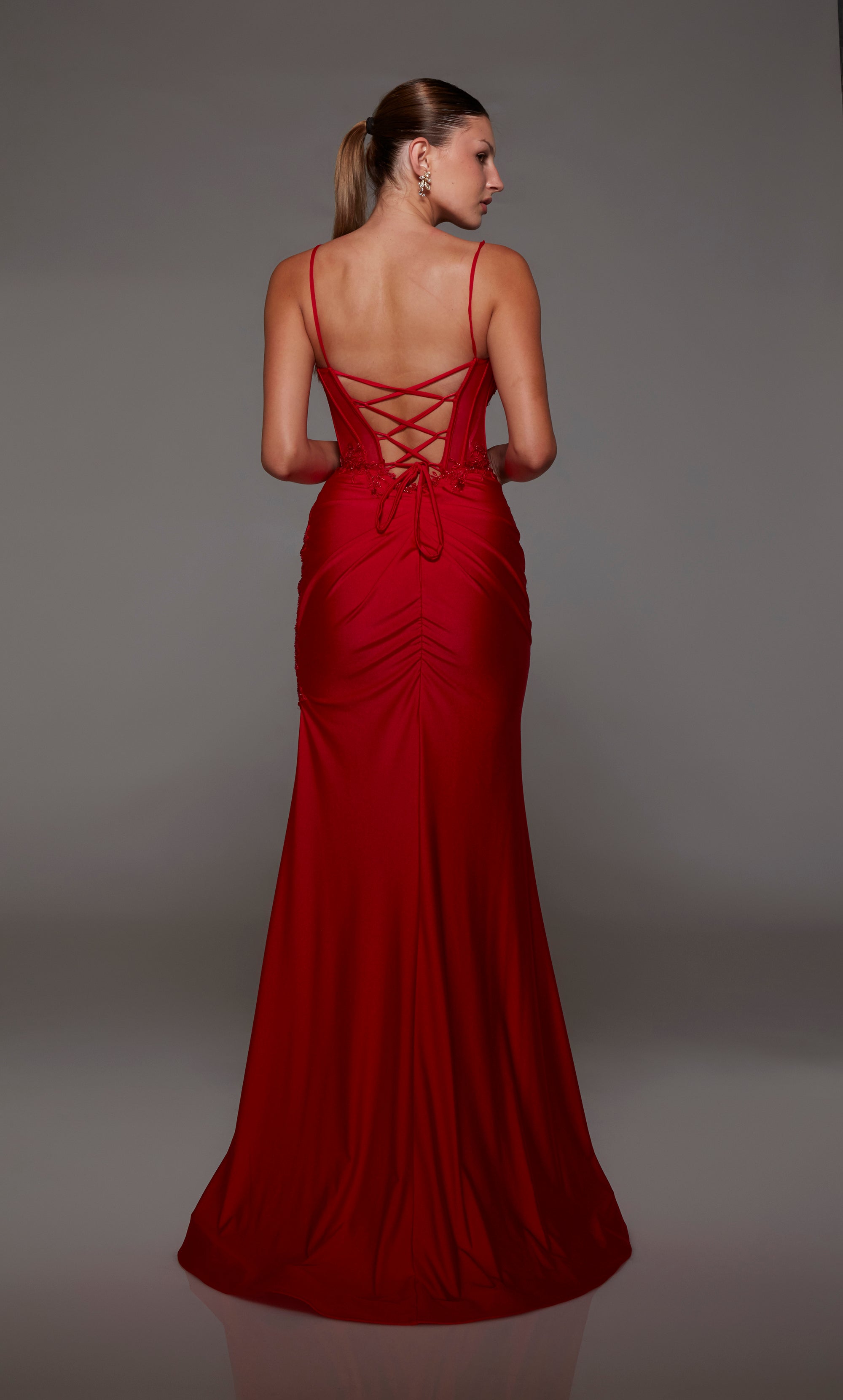Sleek red corset prom dress: sweetheart neckline, sheer bodice, side slit, lace-up back, adorned with lace appliques for an touch of elegance.