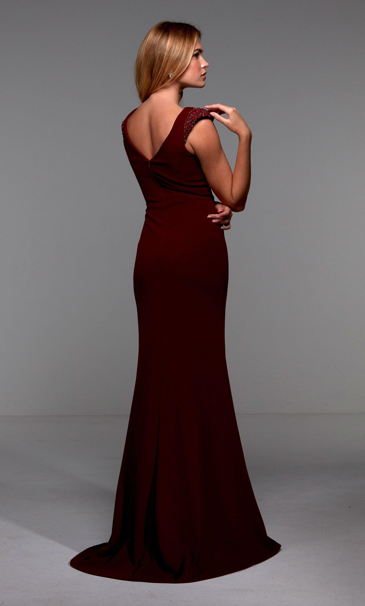 Burgundy long evening dress with beaded capped sleeves, a V shaped back, and train