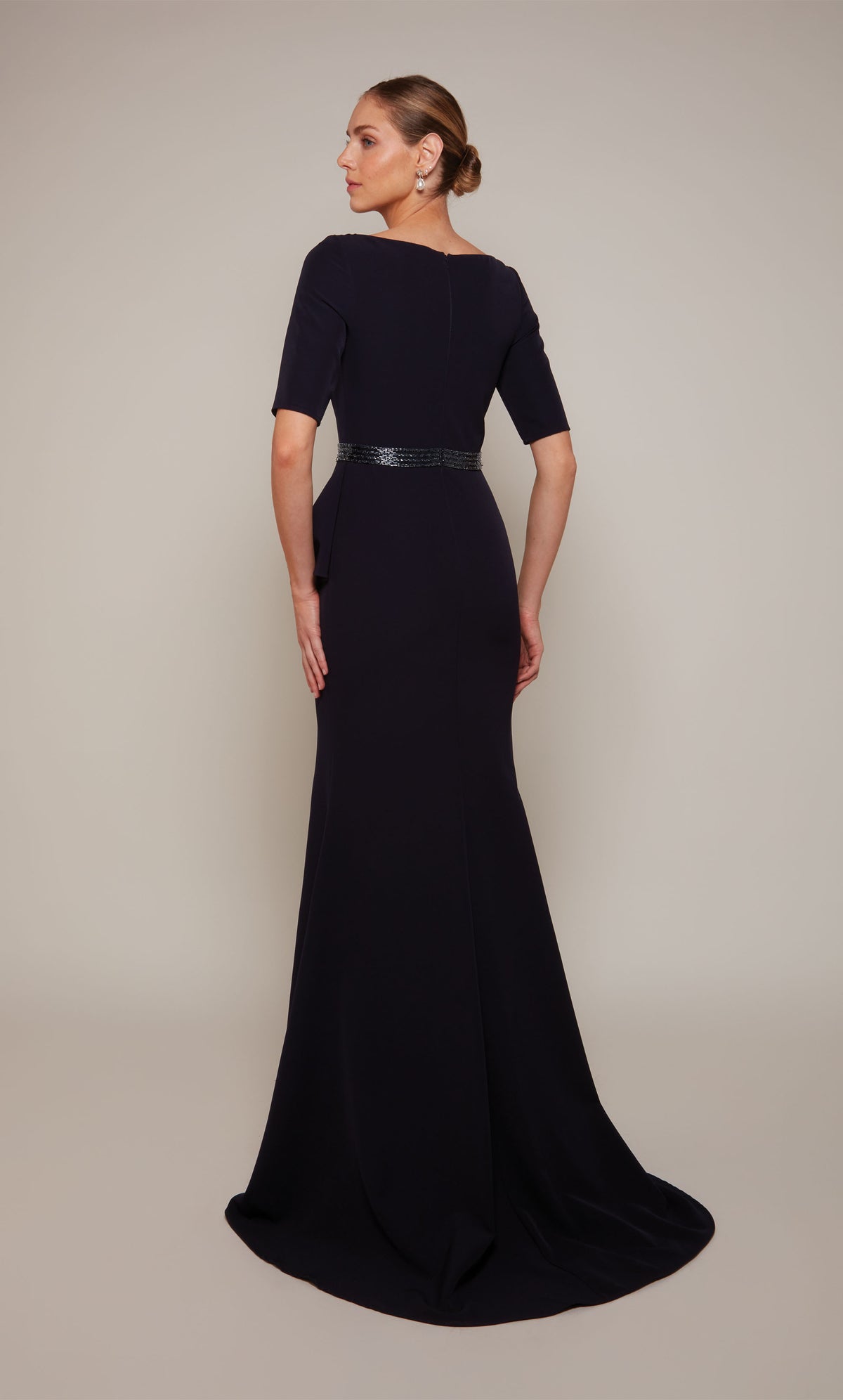 A navy scooped neck designer gown with short sleeves, a closed, zip up back, a beaded waistline, and a train.