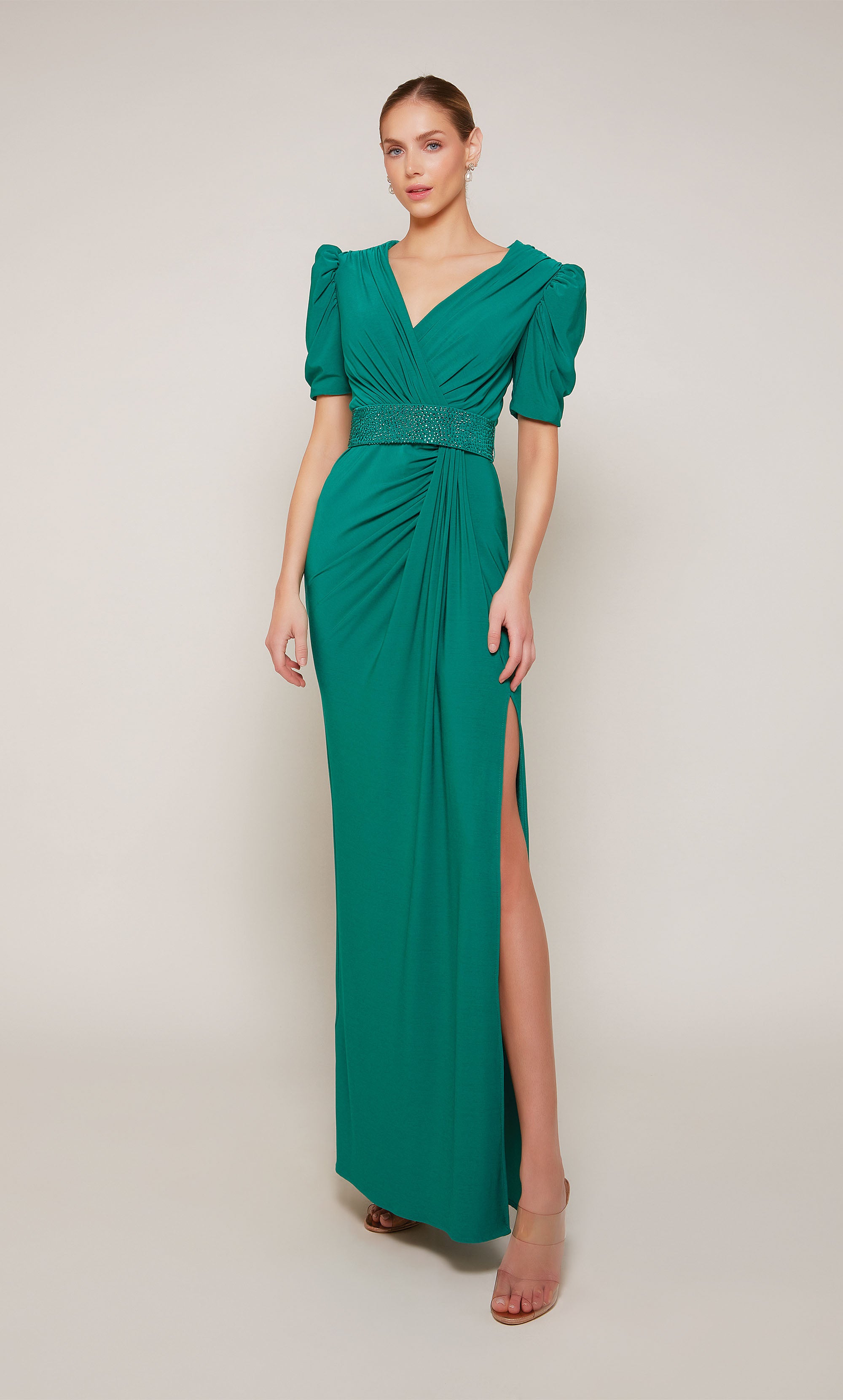 An emerald evening gown with puff sleeves, a V-neckline, an embellished belt, and elegant side slit.