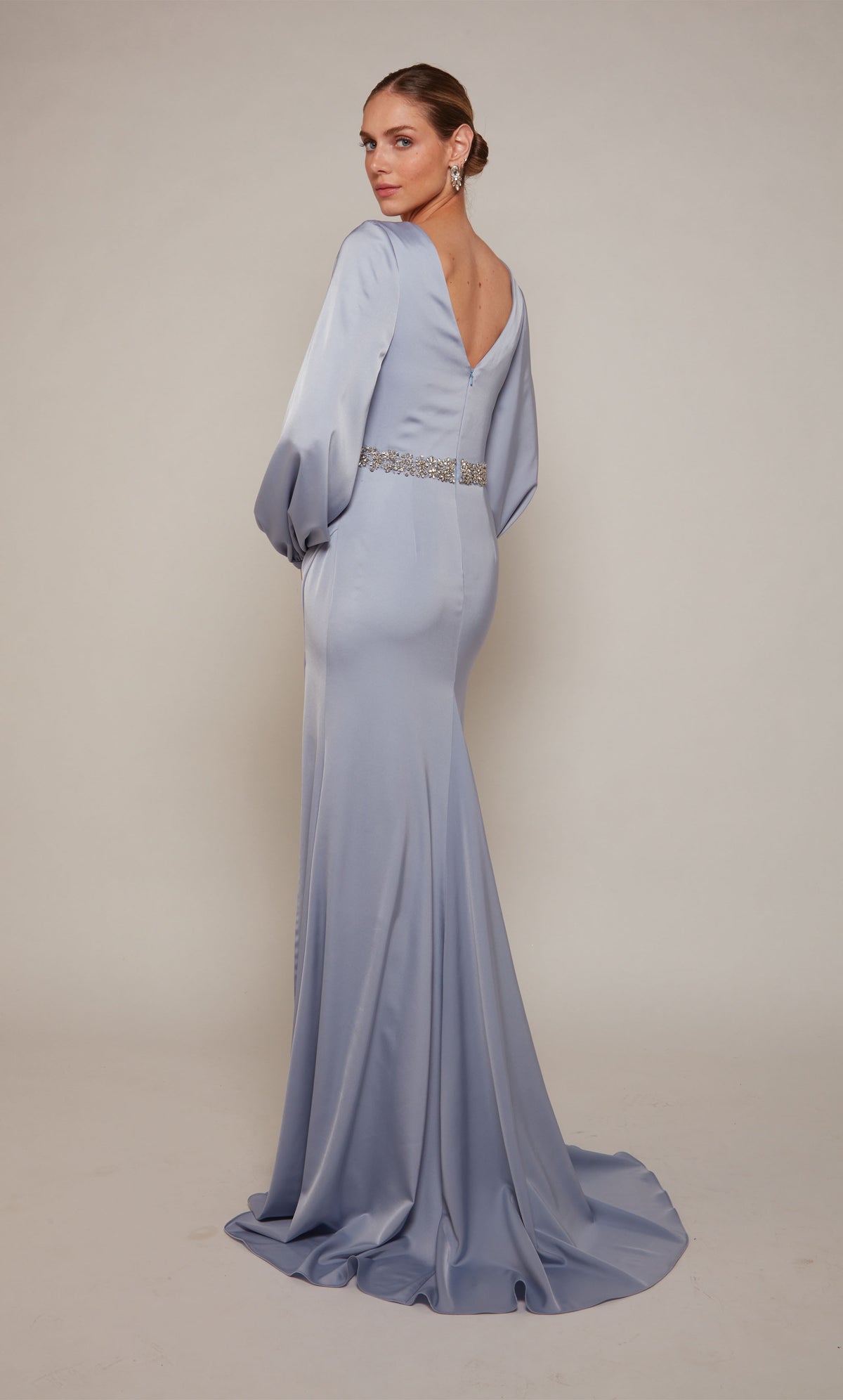 A chic, long sleeve, satin mother of the bride dress with a V-shaped back, jeweled waistline, and train in french blue.