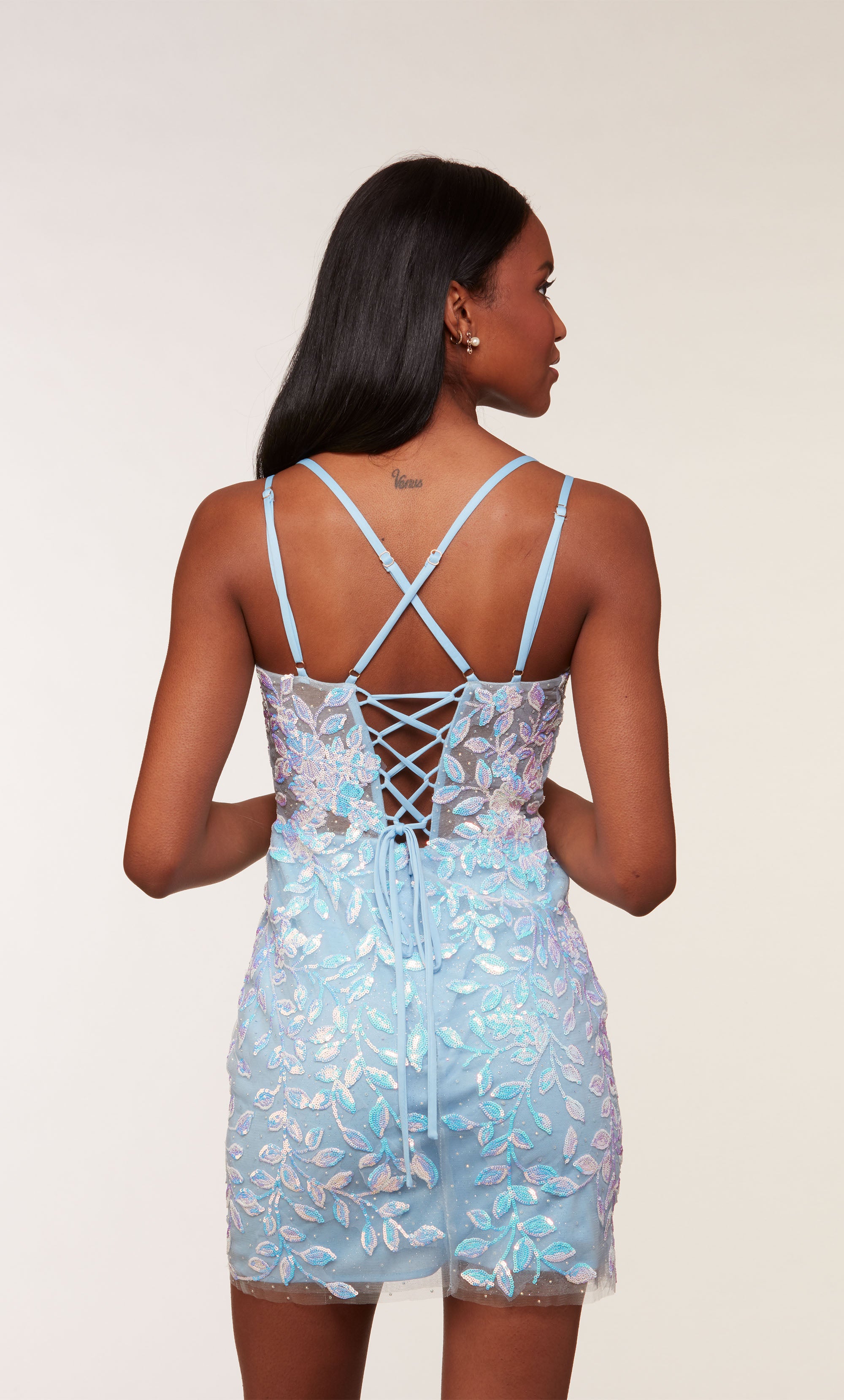 A light blue, fitted short designer dress with a plunging neckline, a sheer bodice, and iridescent sequin embellished floral appliques throughout. 