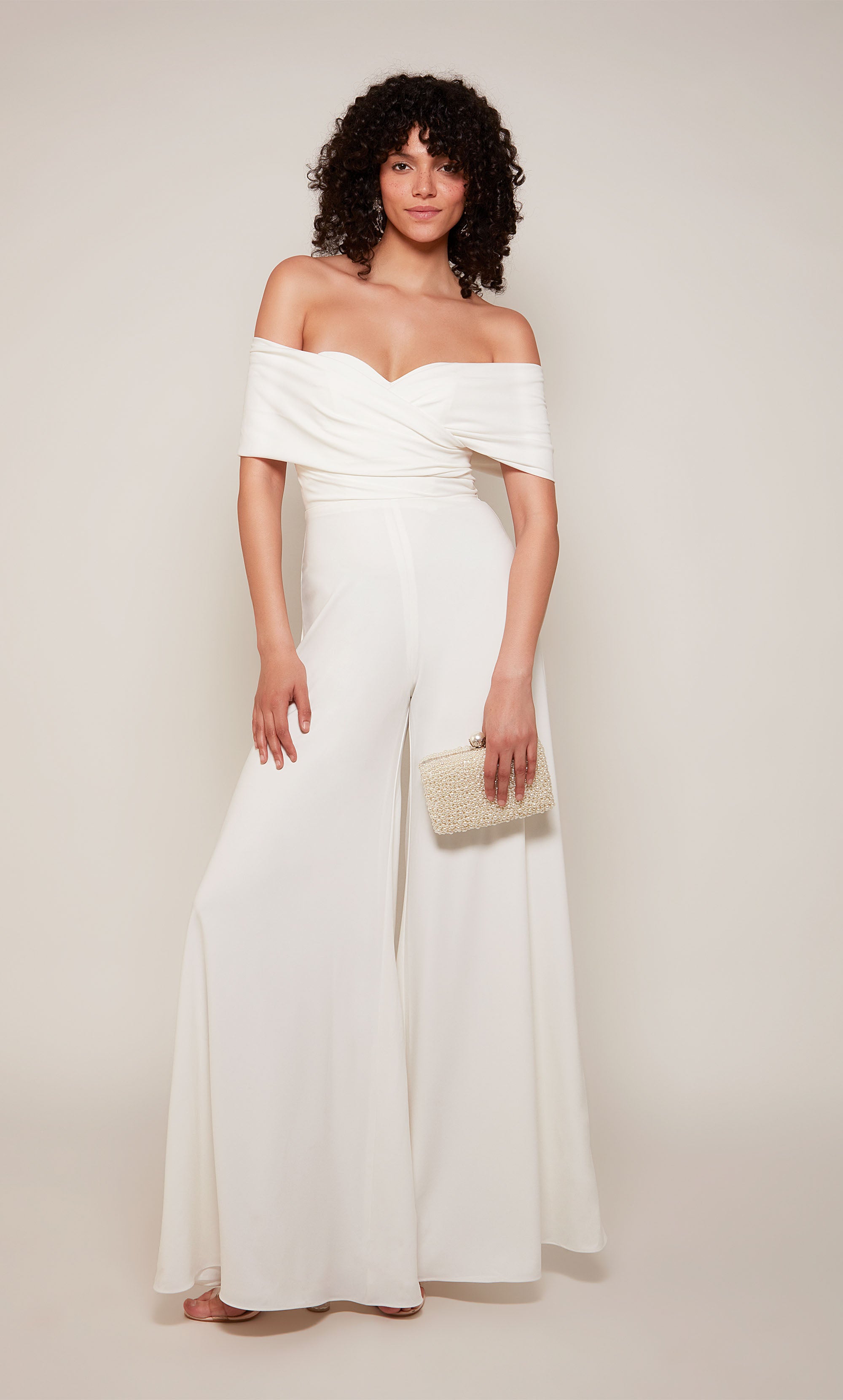 An off-the-shoulder jumpsuit with a wide fit and flare pant in white satin fabric.