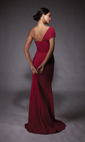 A raspberry pink colored one shoulder evening gown with a cascading ruffle and side slit.