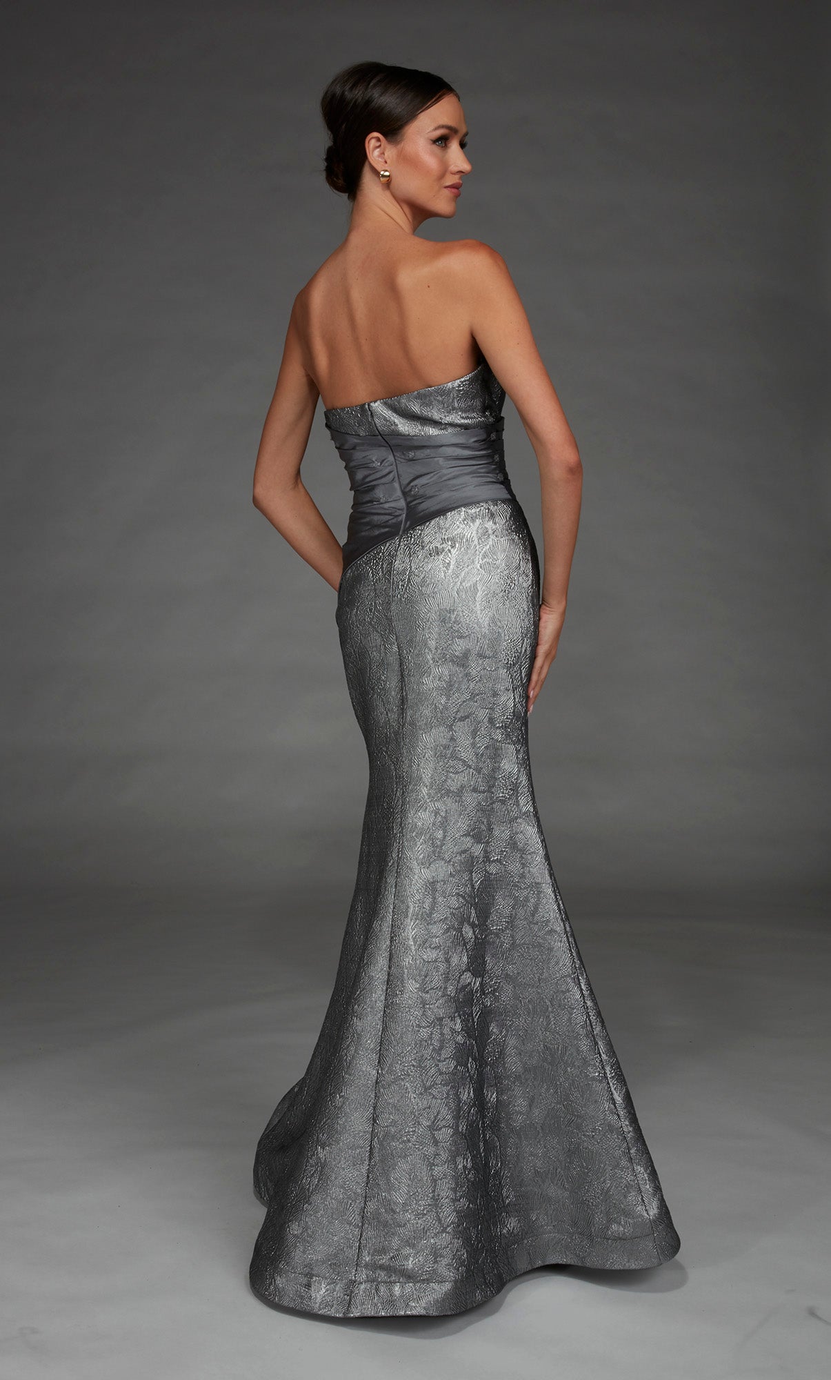 Woman wearing a silver strapless gown against a gray background