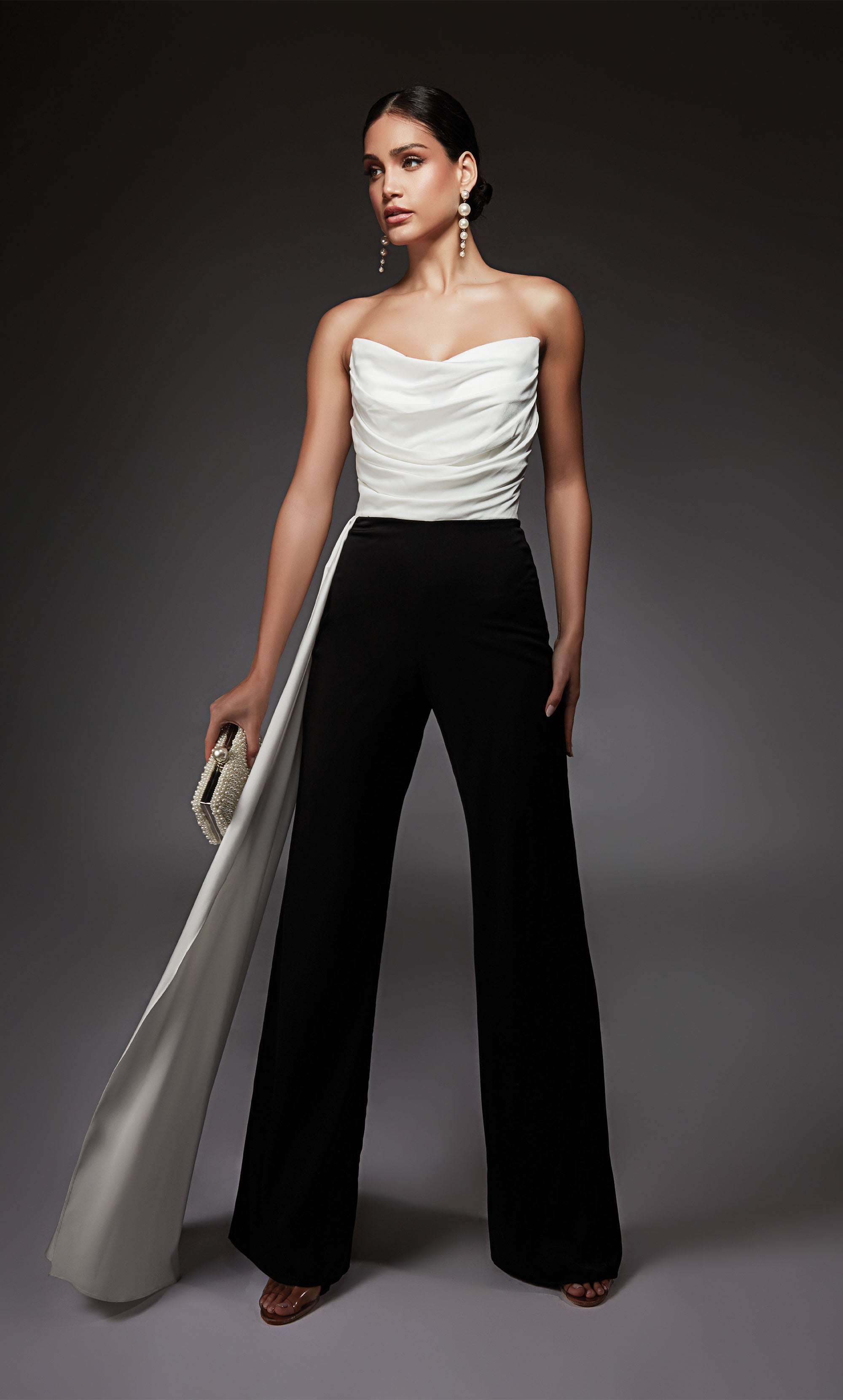 A chic, strapless jumpsuit with a white ruched top and cascading drape, and black wide leg pant.