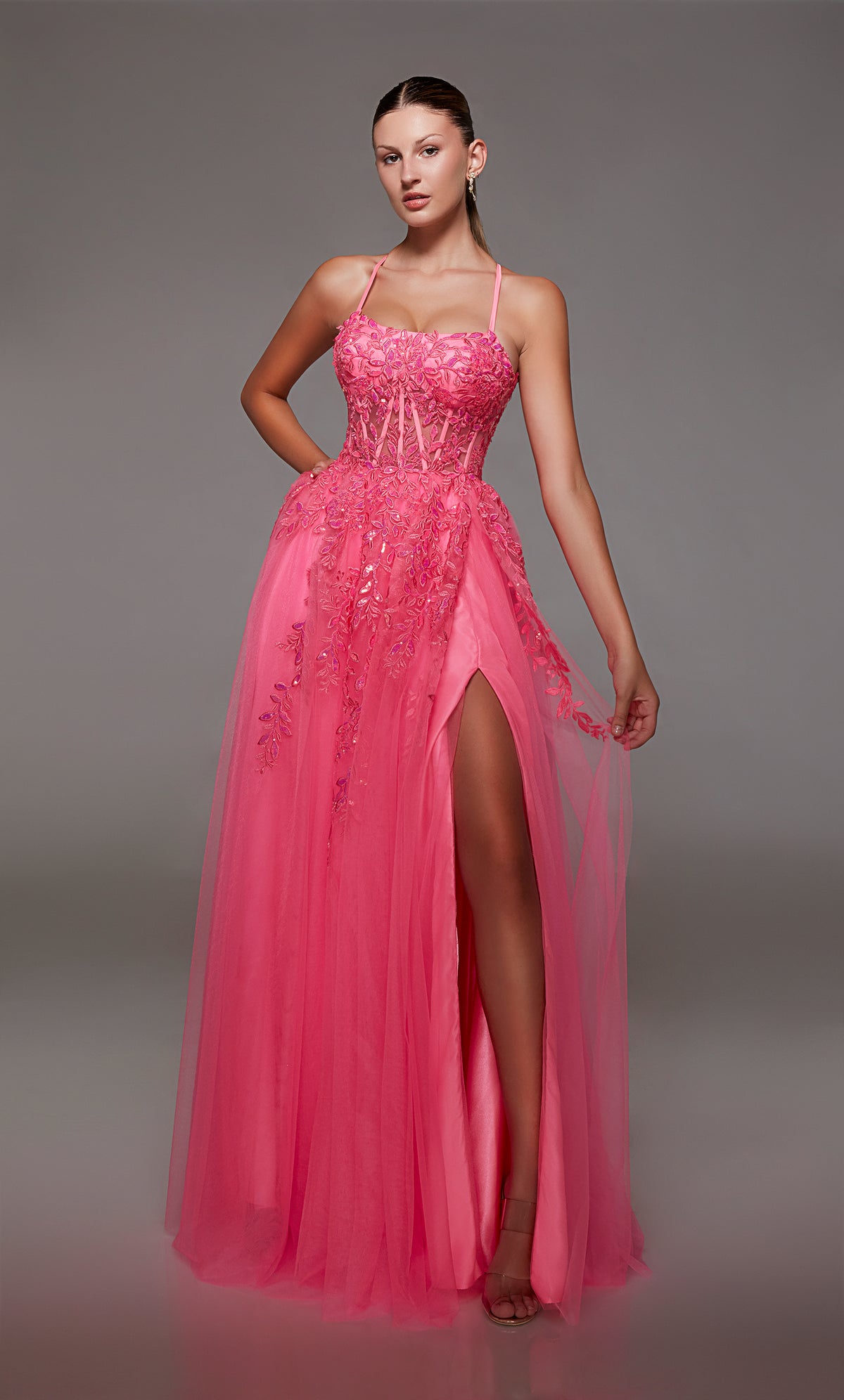 Pink prom dress: sheer corset bodice, full tulle skirt with front slit, lace-up back, and intricate floral lace appliques for an enchanting look.
