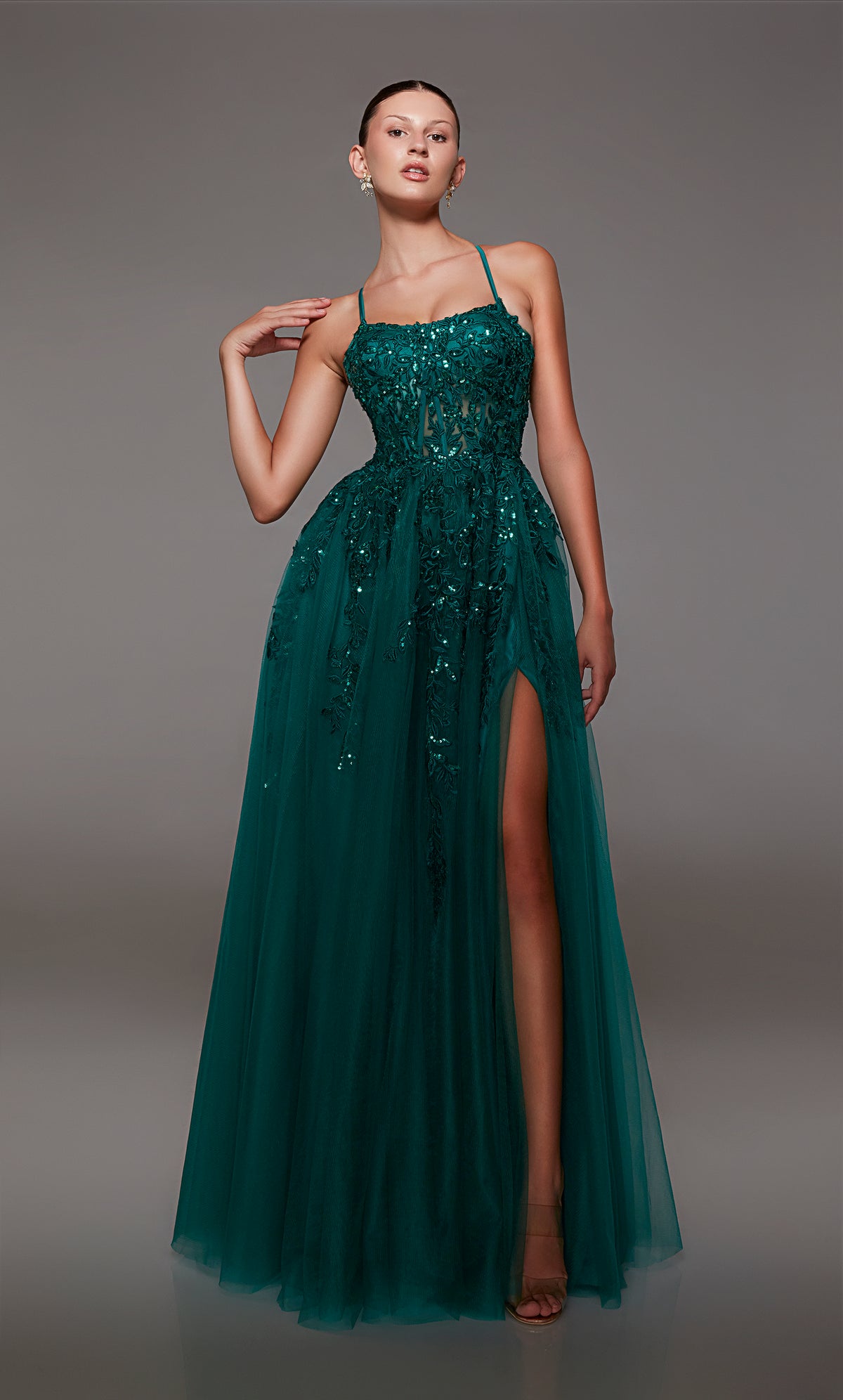 Green prom dress: sheer corset bodice, full tulle skirt with front slit, lace-up back, and intricate floral lace appliques for an enchanting look.