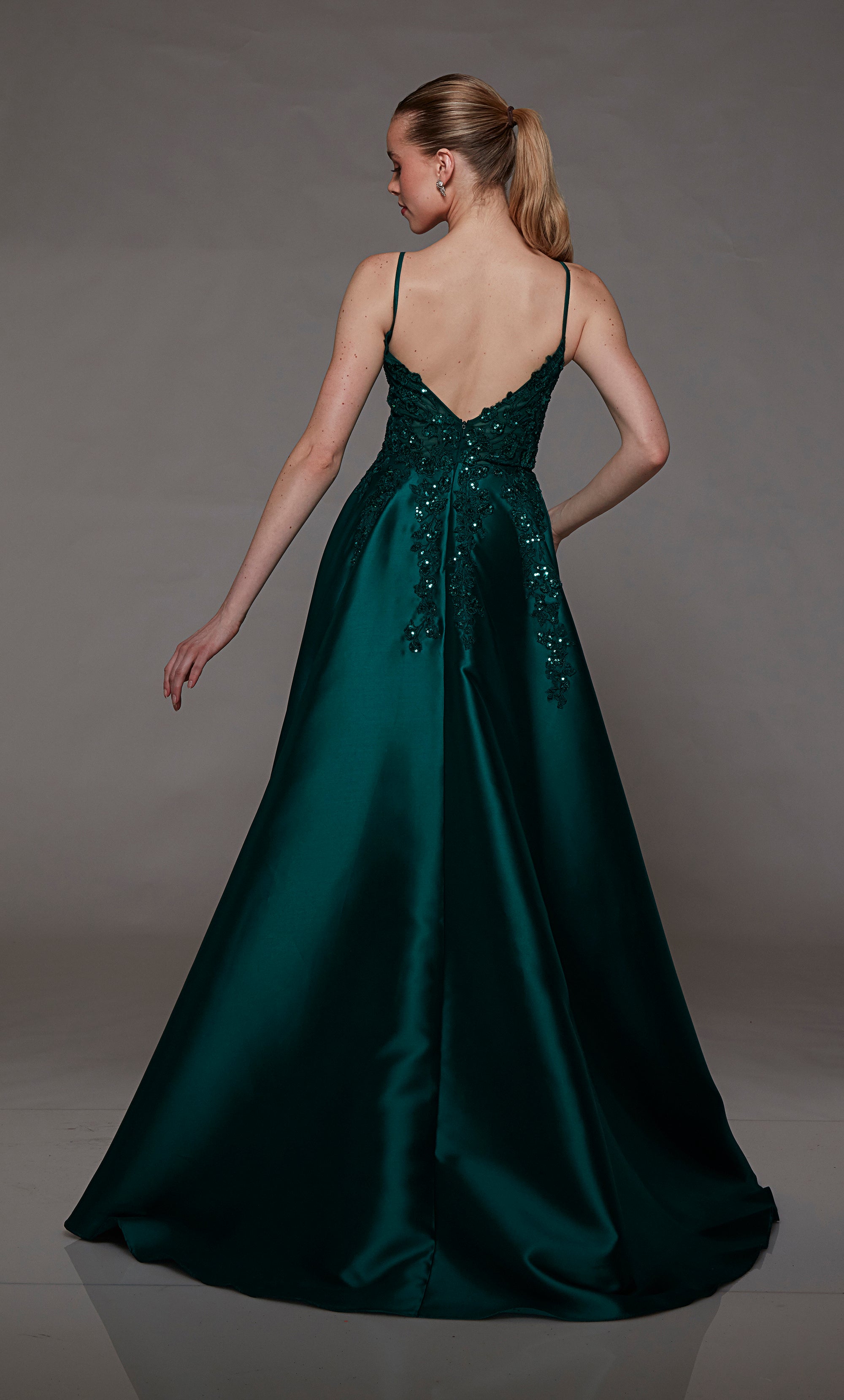 Plunging pine green A-line designer gown featuring an front slit, convenient pockets, sequined floral lace appliques, an stylish V-shaped back, and an subtle train for an chic and modern elegance.