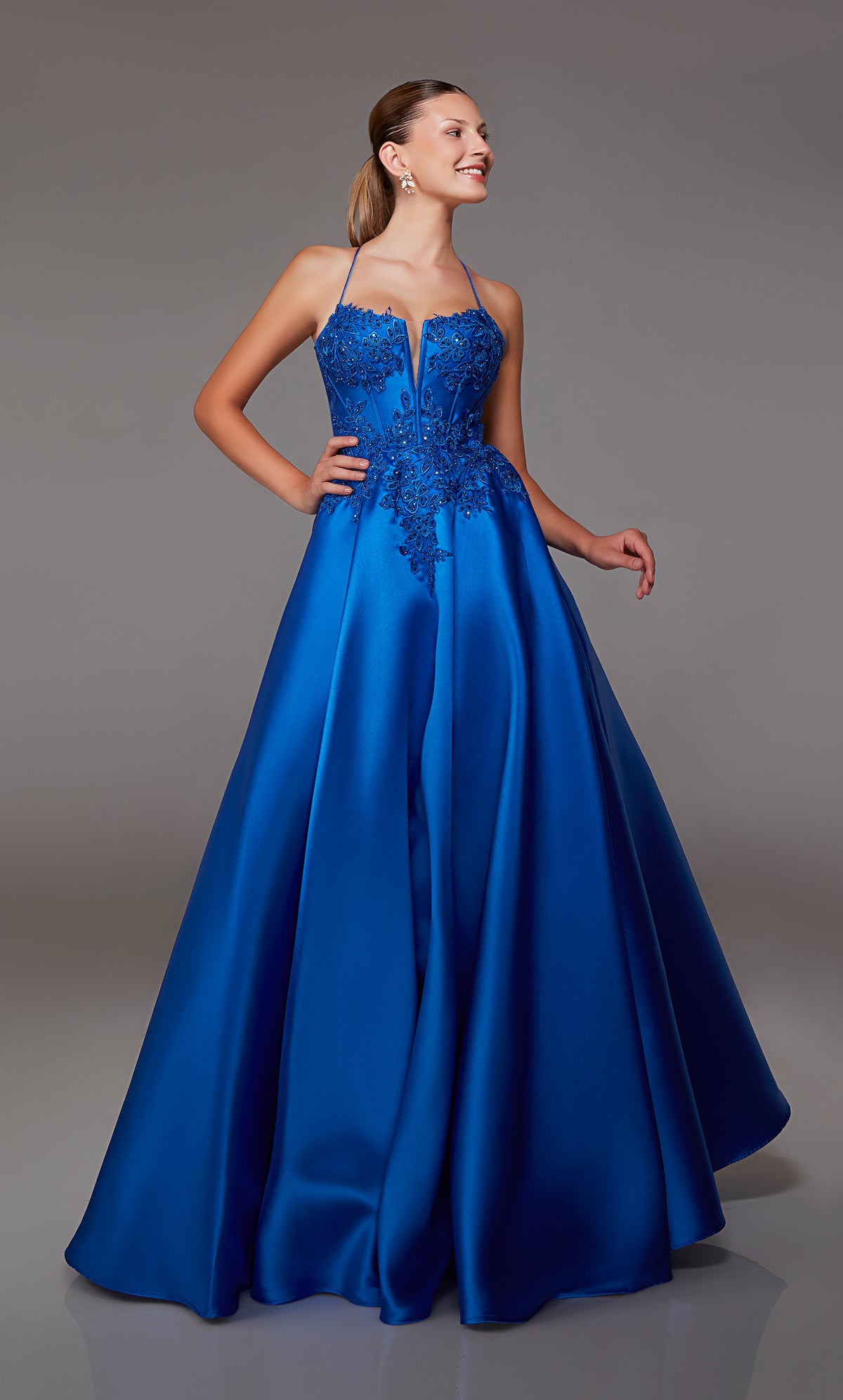 Royal blue ball gown spotlighting an plunging corset bodice with beaded floral lace appliques and an strappy lace-up back for an enchanting and stylish look.