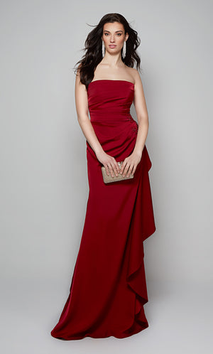 Long strapless evening gown with a side ruffle and lace applique at the hip in red.