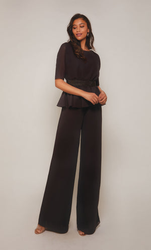 Peplum jumpsuit with short sleeves, an faux beaded belt at the waistline, and wide leg pant in charcoal.