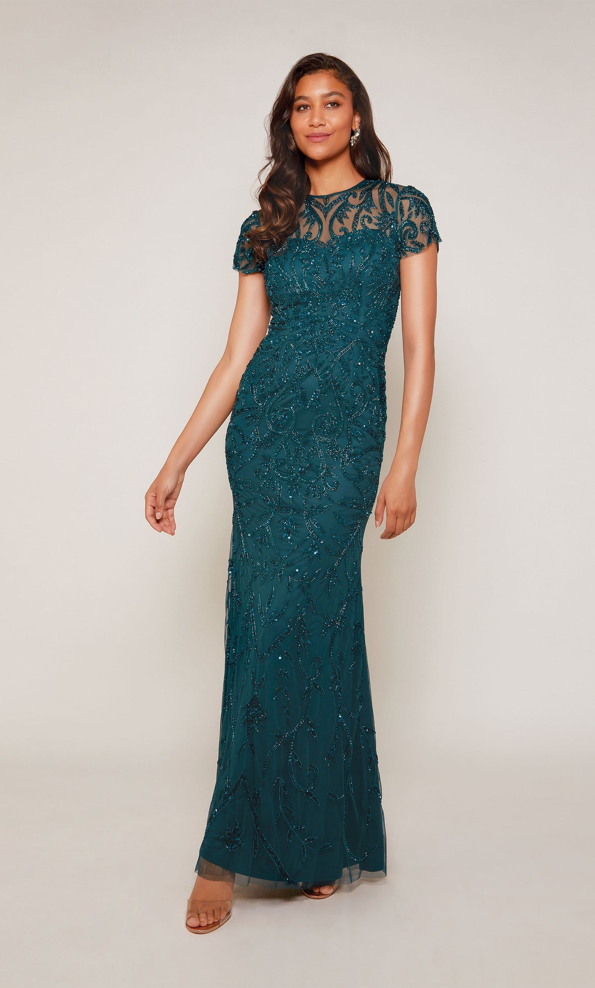 A floor length, hand-beaded evening gown with an illusion neckline and short sleeves in an dark green color called dragonfly.