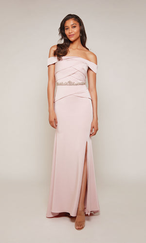 A rosewood colored, off the shoulder evening gown with an pleated bodice, beaded waistline, and side slit.