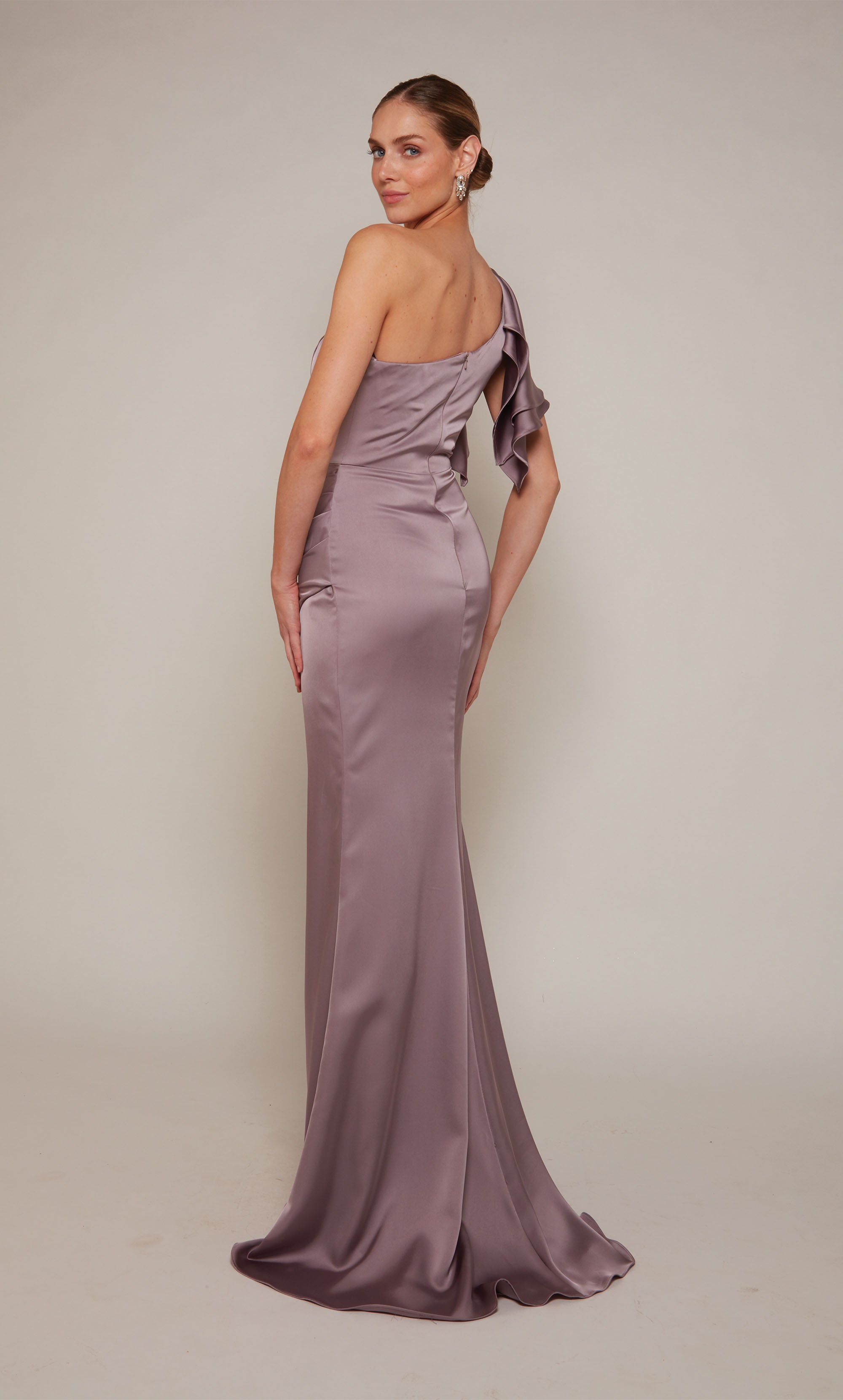 A satin, one shoulder ruffle dress with a pleated skirt and front slit in a dusty purple looking color called smoke.