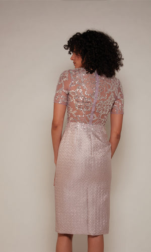 A knee length mother of the bride dress with an illusion closed back and short sleeves in a light pink colored Jacquard.
