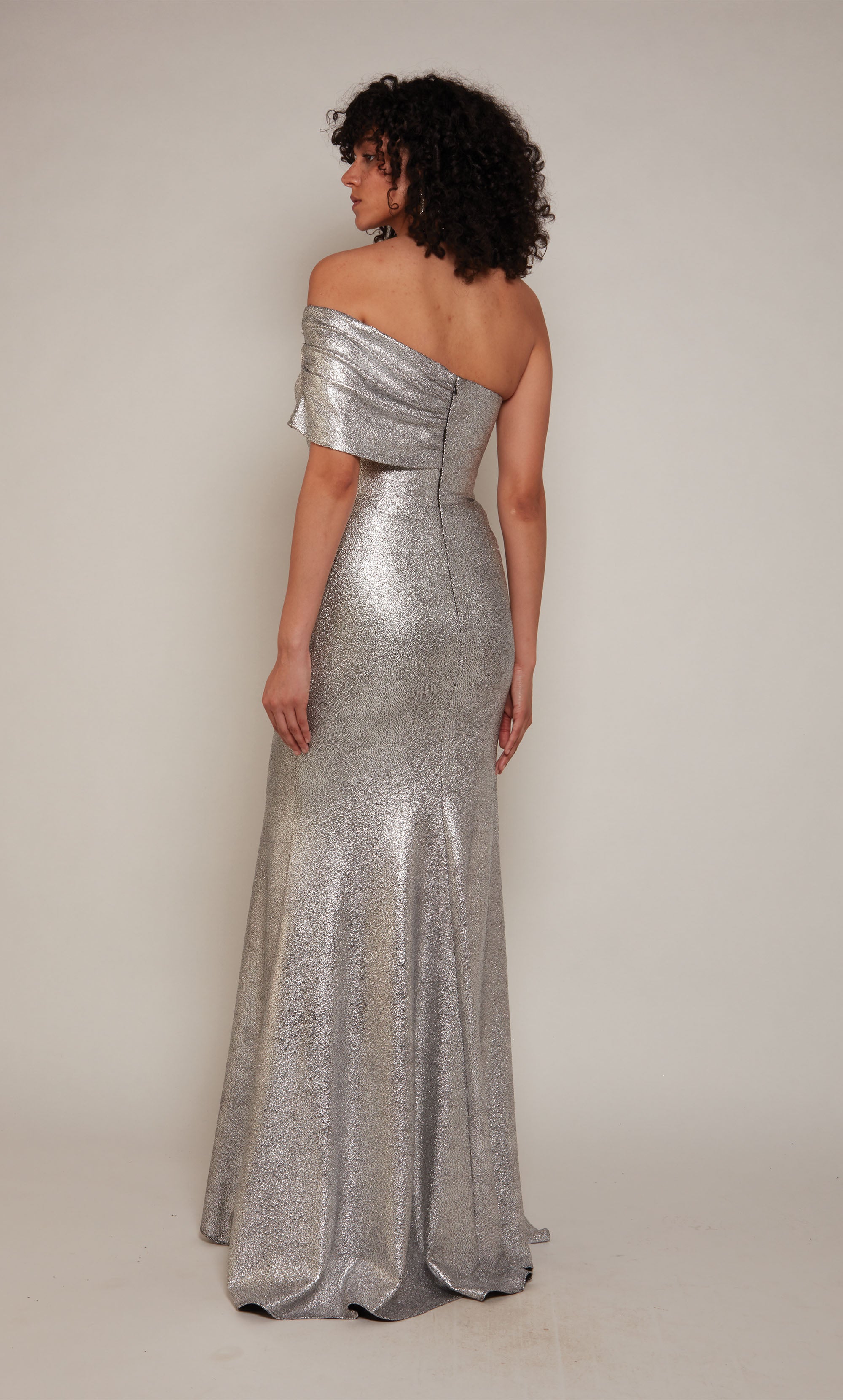 A silver evening gown boasting a one shoulder neckline, a front slit, and a detachable side drape.