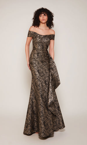 A black and gold Jacquard formal gown with an off the shoulder, twist neckline and a cascading side ruffle.