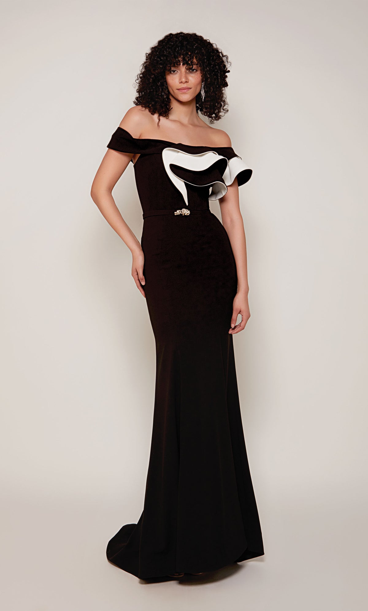 A black and white evening gown with an off-the-shoulder neckline and ruffle bodice. In addition, the dress has a faux belt at the waistline and a slight train.