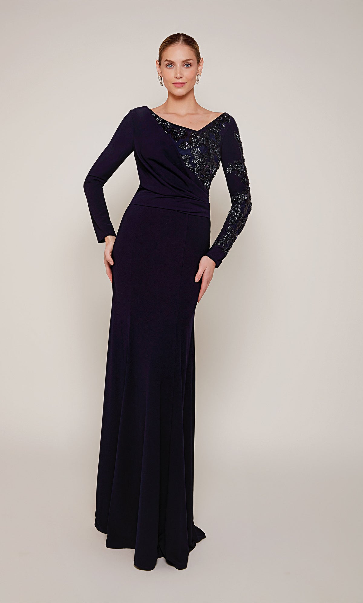 A navy long sleeve mother of the bride dress with an off center V-neckline and silver beaded detail on the left side of the bodice and sleeve.