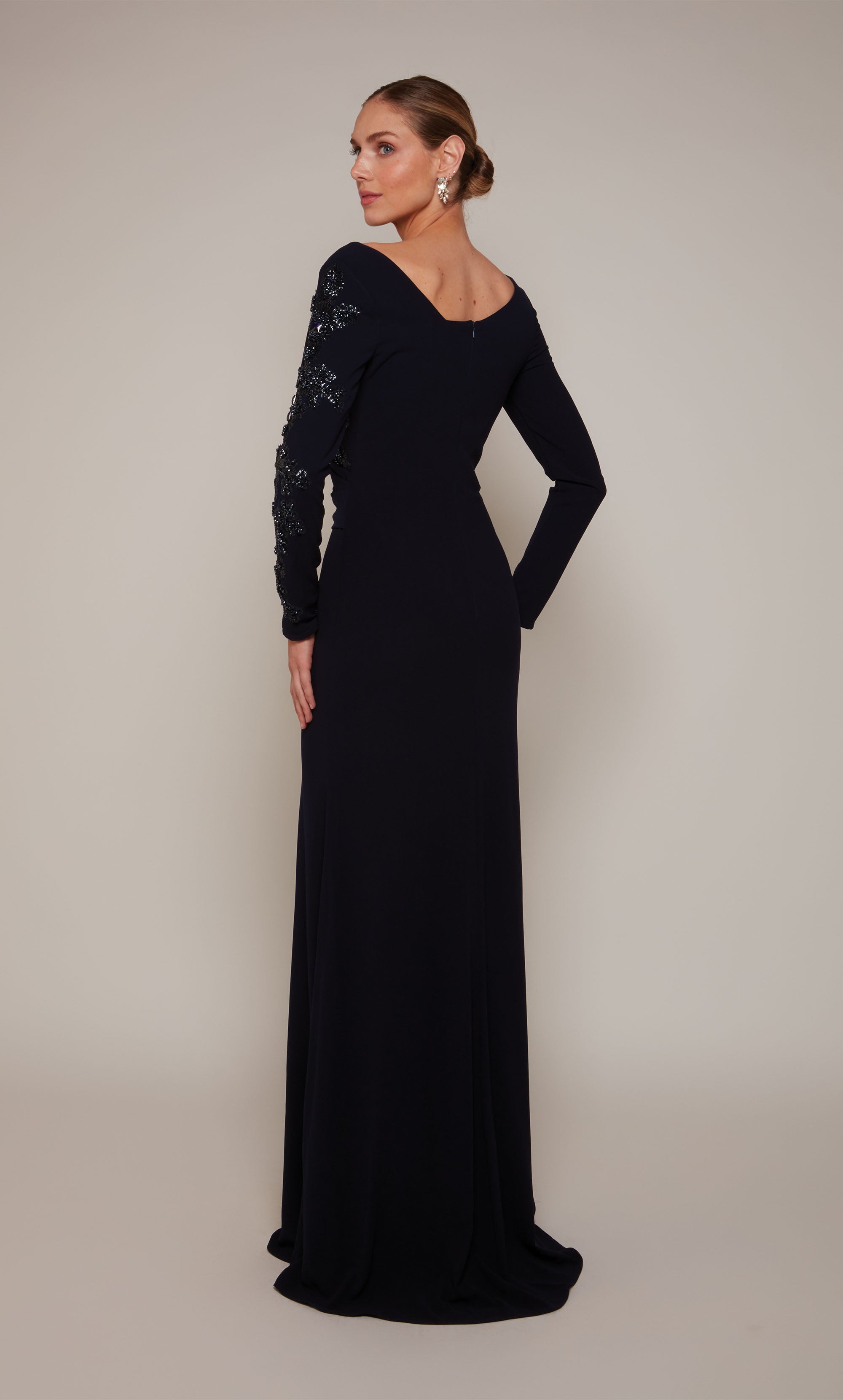 A navy long sleeve mother of the bride dress with an off center V-neckline and silver beaded detail on the left side of the bodice and sleeve.