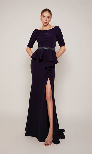 A navy scooped neck designer gown with a peplum short sleeve bodice, a beaded waistline, a side ruffle, and side slit.