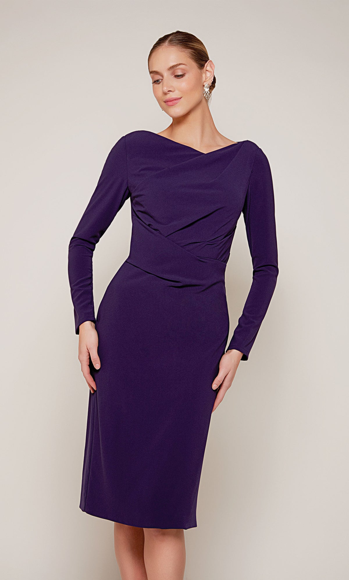 A knee length cocktail dress with long sleeves and an off center V-neckline in dark purple.
