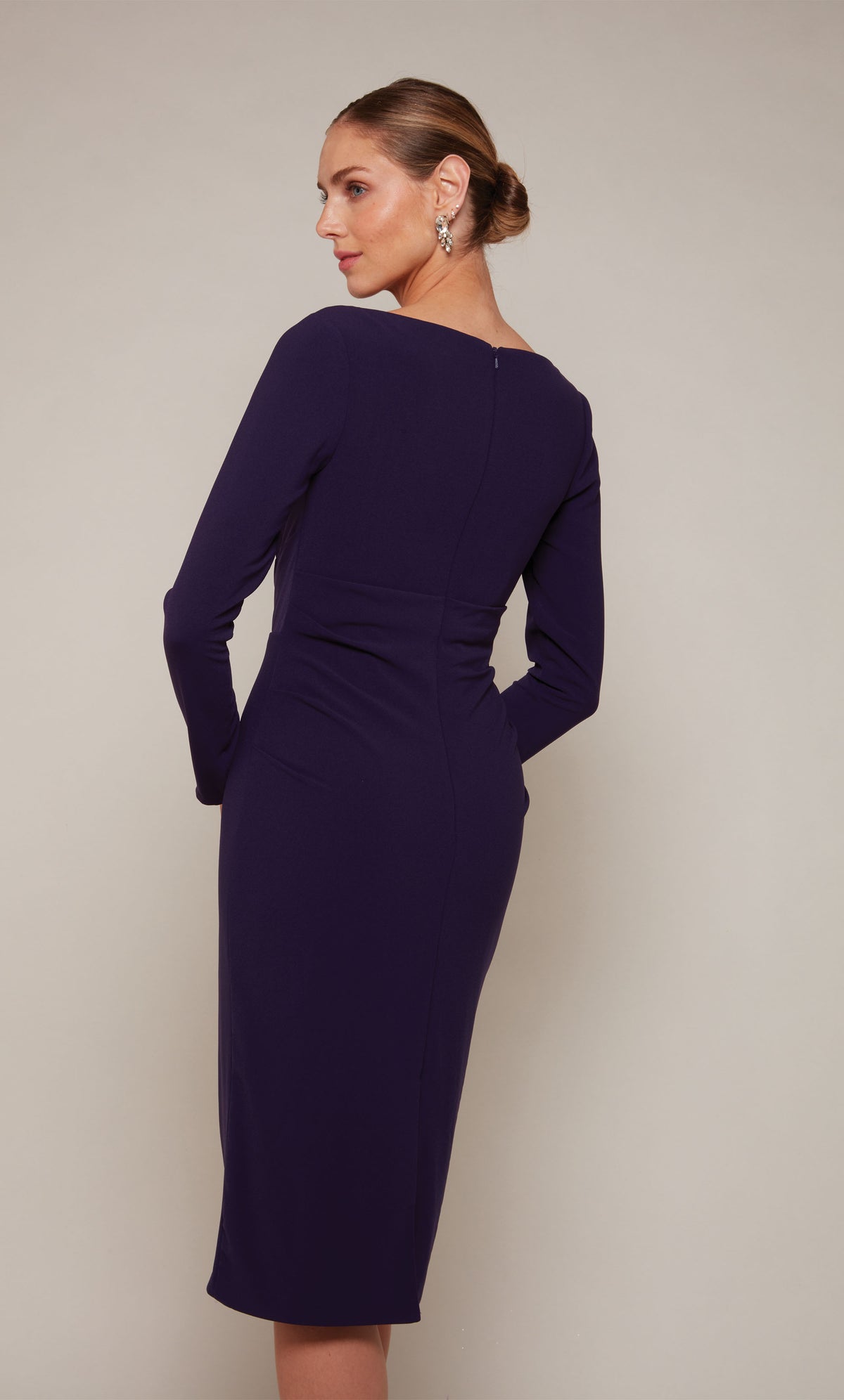 A knee length cocktail dress with long sleeves and a closed zip-up back in dark purple.