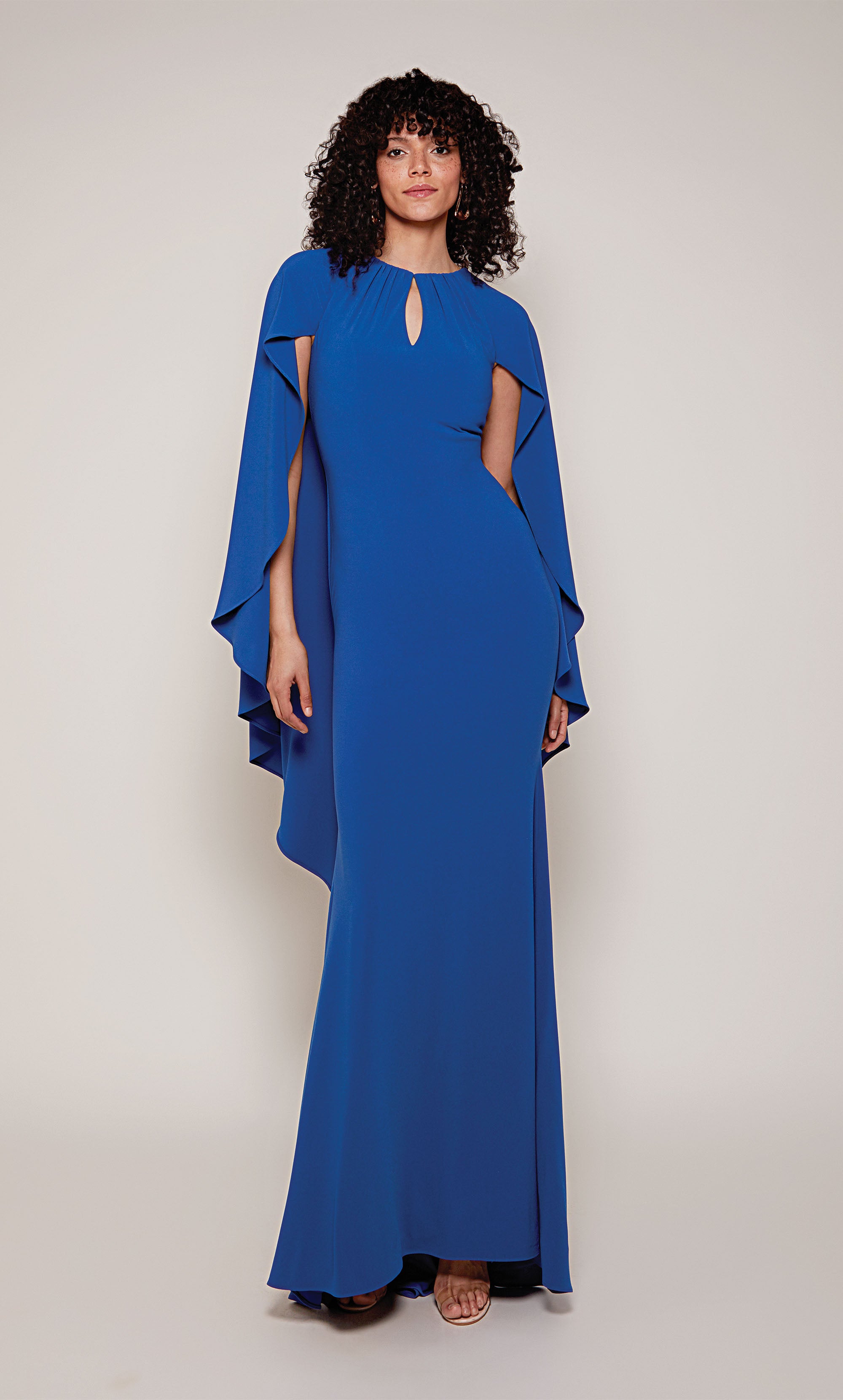 A long, fitted capelet dress with a front key hole and slightly flared skirt from knee to hemline in royal blue.
