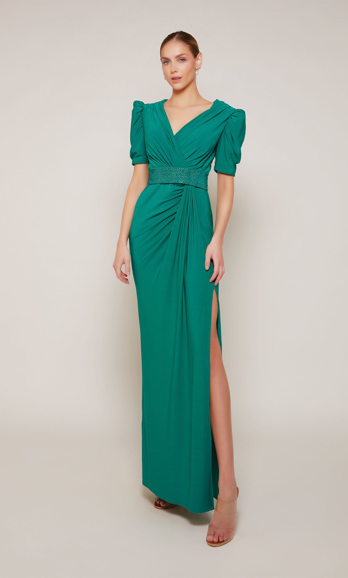 An emerald evening gown with puff sleeves, a V-neckline, an embellished belt, and elegant side slit.