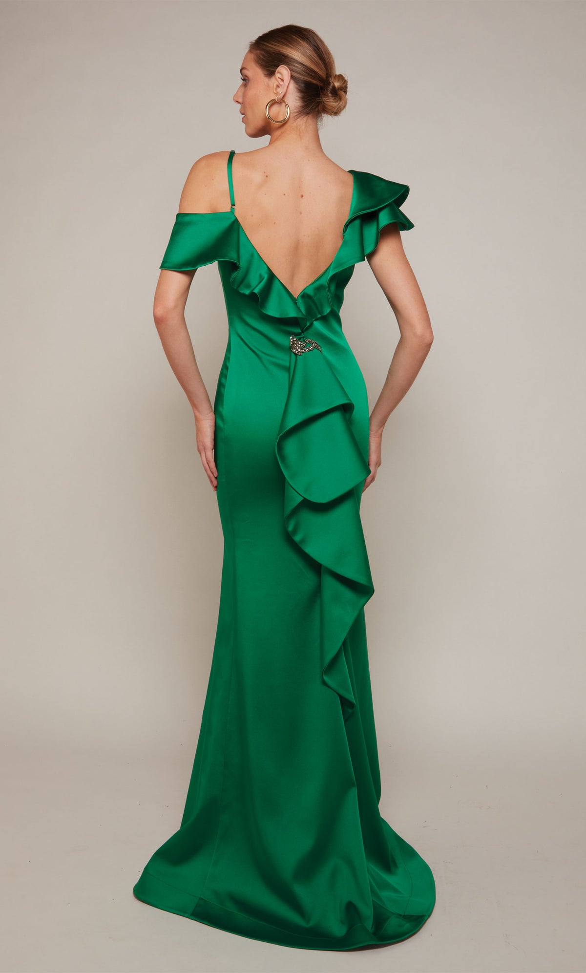 A satin formal dress featuring a one shoulder neckline, a fitted silhouette, and ruffles in emerald green.