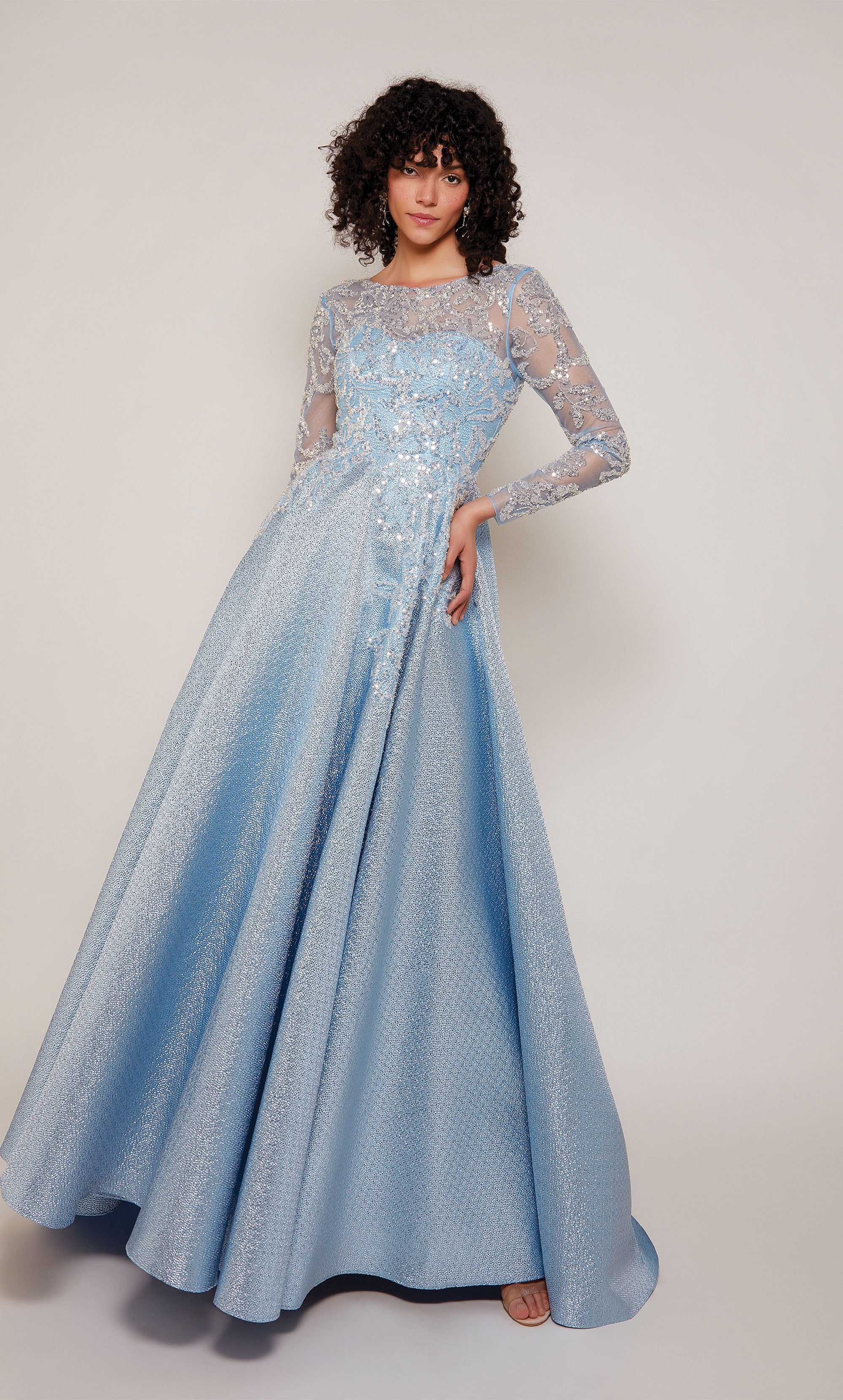 A french blue A-line mother of the bride gown with long sleeves and an illusion semi-sweetheart neckline. The bodice of the dress has a beautiful embellished tulle overlay.