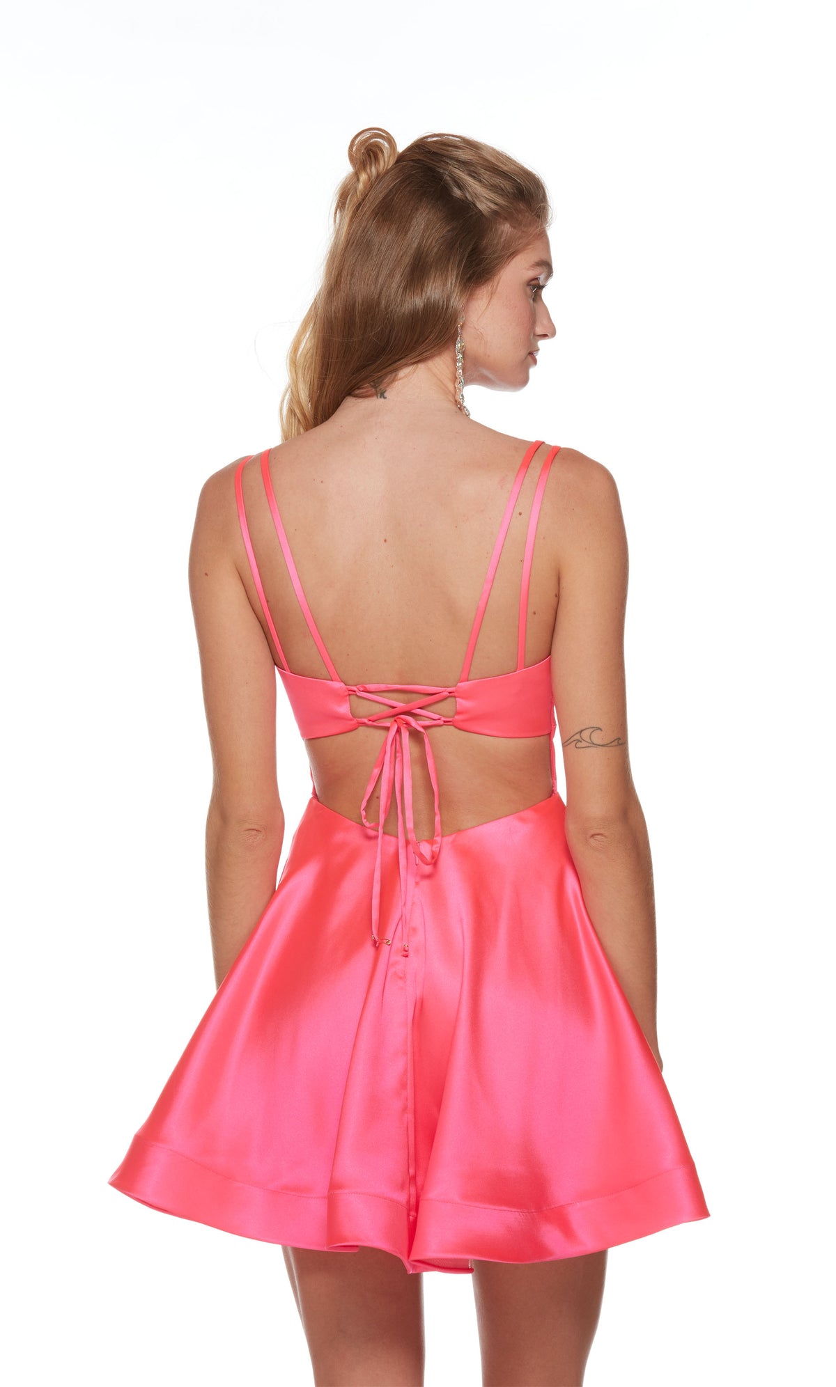 A V-neck, short satin homecoming dress with double spaghetti straps and a strappy, lace-up back in the color barbie pink.