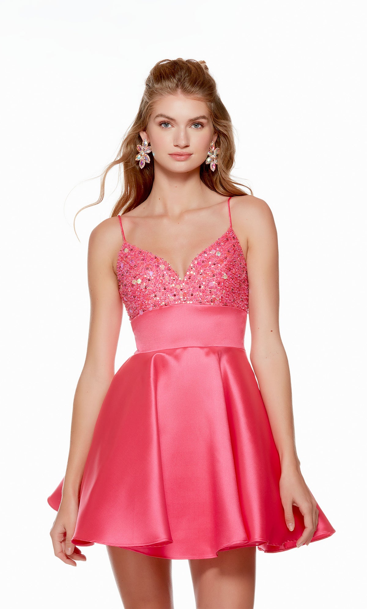 A playful hot pink homecoming dress, featuring a soft V neckline, an open V shaped back, and a flared skirt. The top of the dress is embellished with iridescent beads for a touch of sparkle.