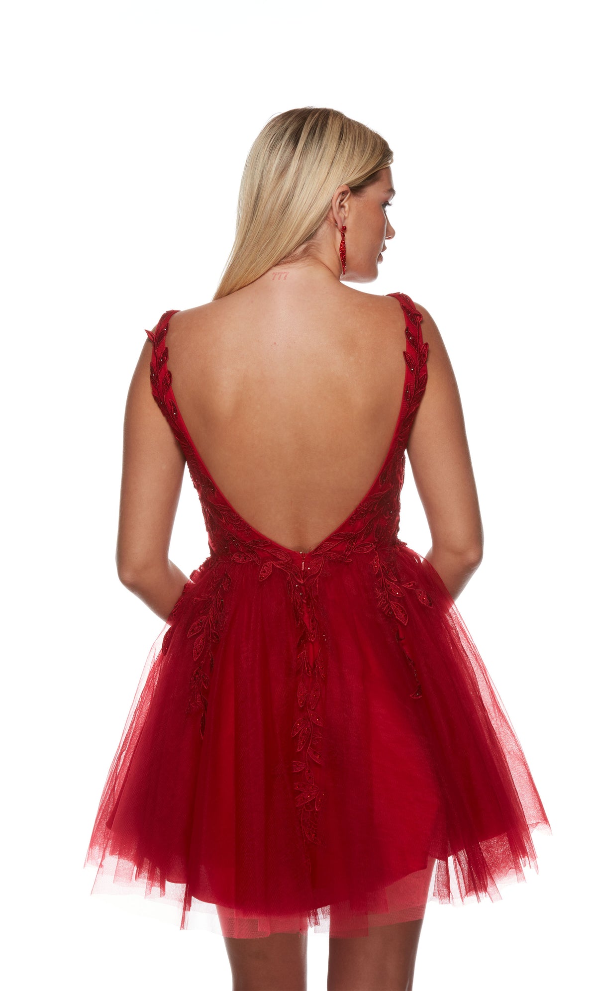 A red, open back short formal dress with floral appliques and a fitted waistline. The skirt is made of layered tulle.
