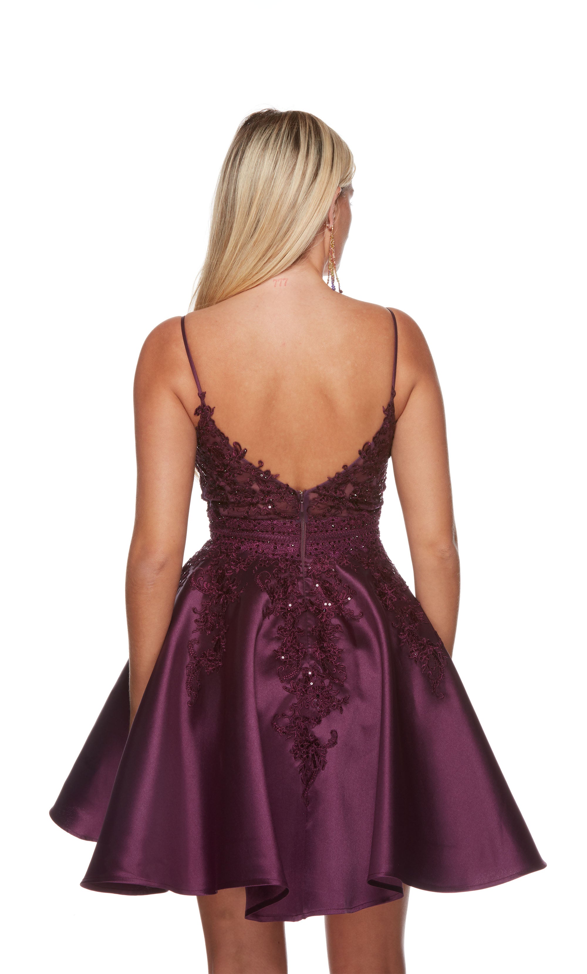 A fun and flouncy A-line dress with a slightly scooped neckline, adorned with intricate lace appliques and sequins for a touch of sparkle. The color is a rich black plum.