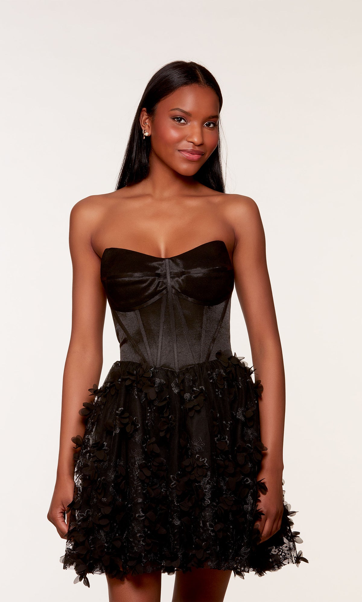 A black strapless satin corset dress, showcasing a fitted bodice and a flared skirt adorned with intricte 3D flowers.