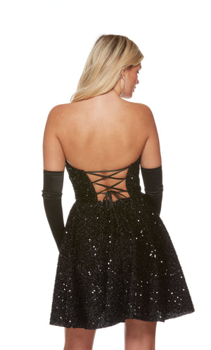 A stunning black sequin short formal dress highlighting a strapless corset top and a flared A-line skirt. The dress is styled with a pair of satin gloves for an extra polished and interesting look. Gloves are not included with the purchase.