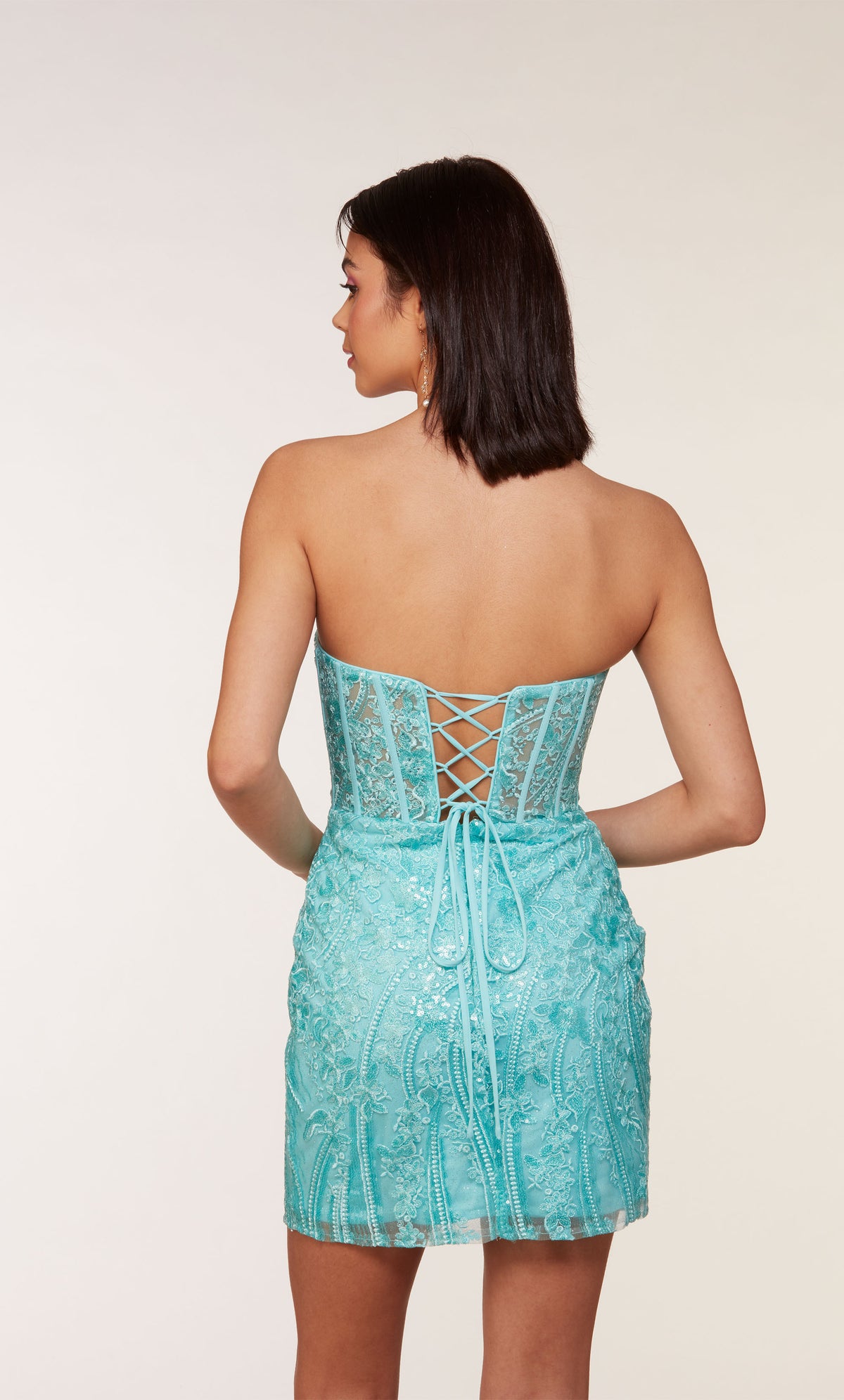 A short strapless corset dress with a lace-up back and a sheer bodice adorned with an intricate lace overlay and a side slit. The dress was created in a refreshing turquoise-like blue called blue radiance.