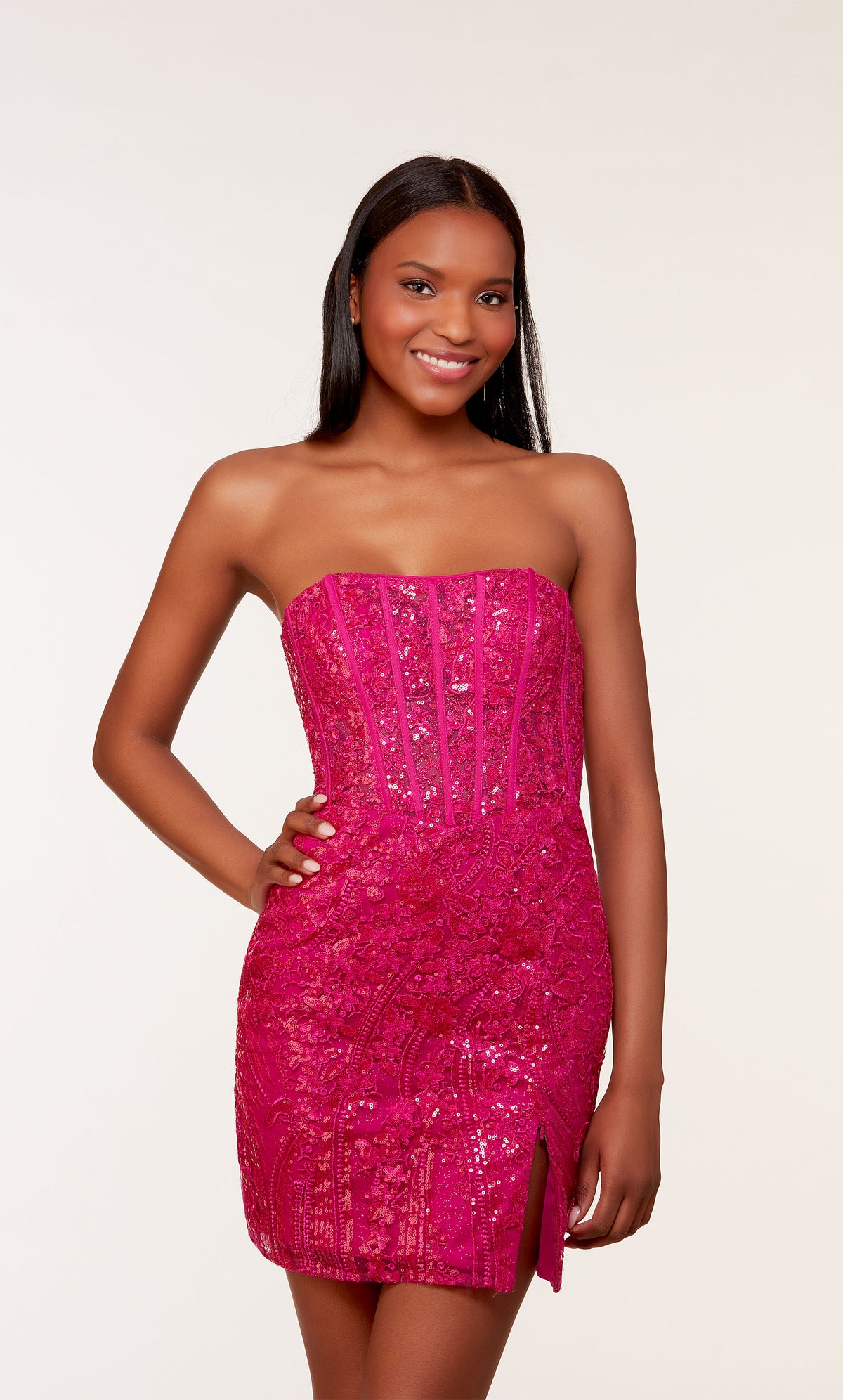A short strapless corset dress with a sheer bodice adorned with an intricate lace overlay and a side slit. The dress was created in a rich raspberry color.