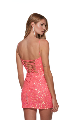 A sparkly light neon pink sequin homecoming dress with a low neckline, side ruching, and a flirty asymmetrical hemline, sure to turn heads at the event.