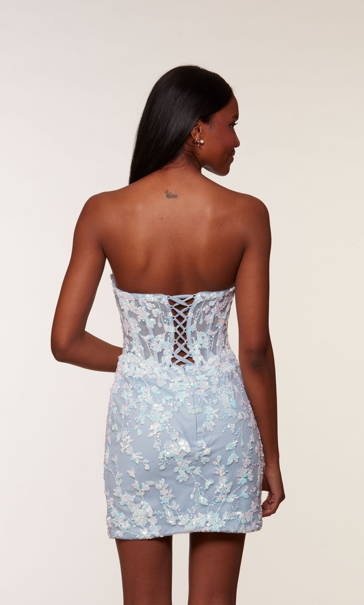 An opal-ice blue, strapless corset dress with a sheer bodice, lace-up back, and floral sequin detail.