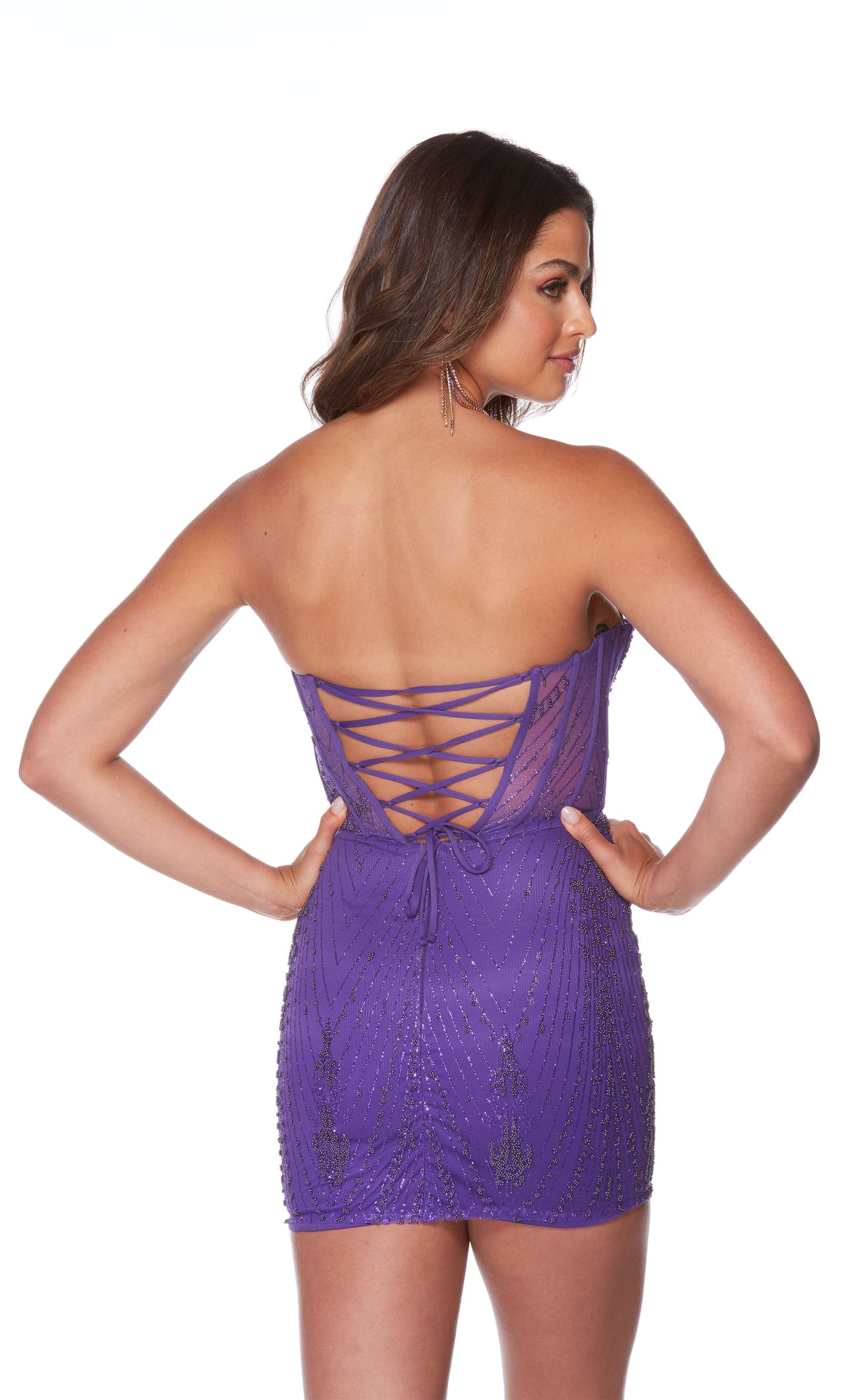 A purple short corset dress spotlighting a strapless sweetheart neckline, sheer bodice, and glitter embellishments throughout. The back of the dress has a lace-up back for a custom fit.