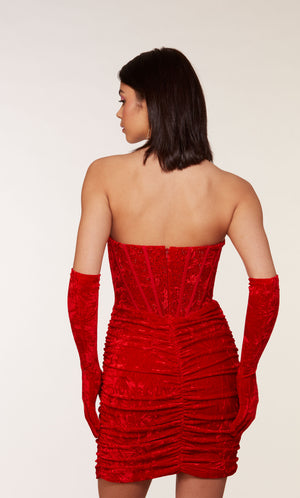 An 80's inspired red velvet corset dress with a strapless neckline and a ruched skirt. The matching gloves level up this chic look.