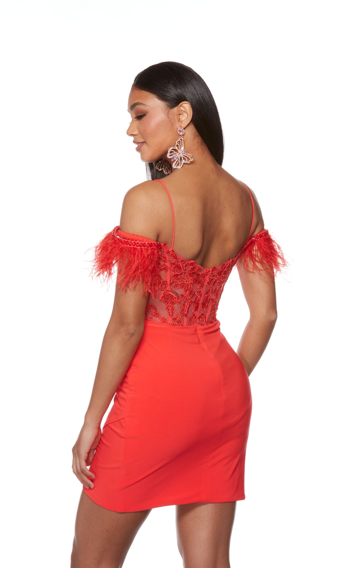 A spicy red corset dress with a sheer lace bodice, feather trim sleeves, and spaghetti straps. The skirt has a fun asymmetrical hem and is crafted from a stretchy, Jersey fabric.
