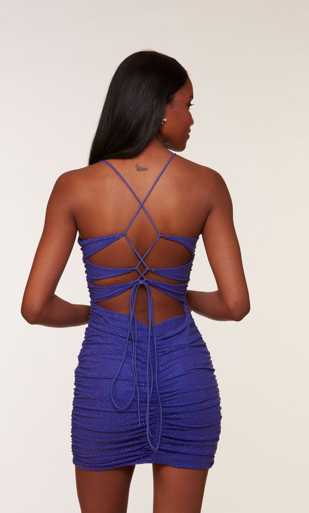 A short, mesh homecoming dress with a V-neckline and ruching detail. The back of the dress has a lace-up back closure for the perfect fit.