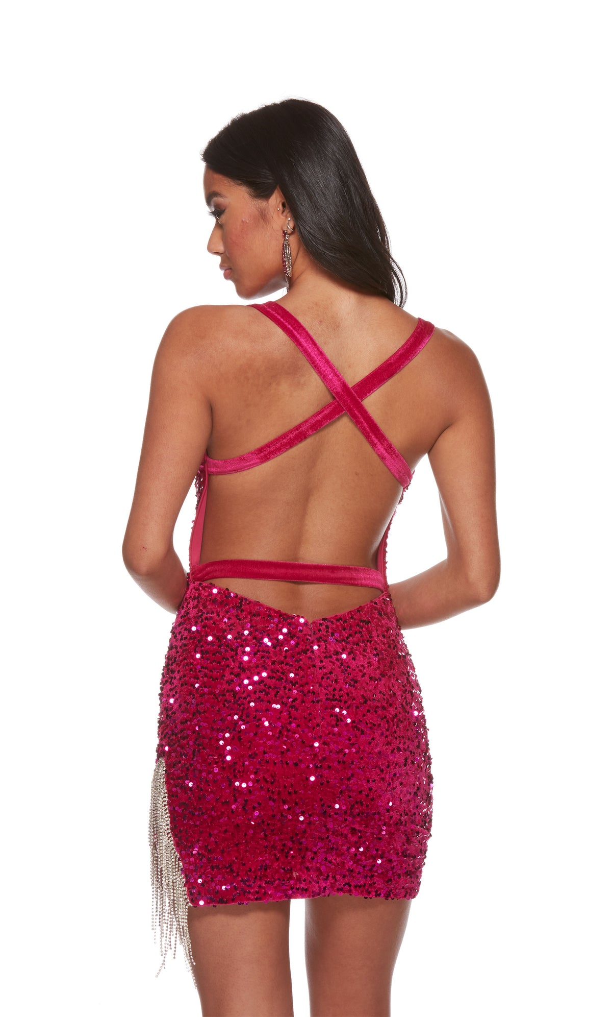 A raspberry colored, halter neck short formal dress made of soft, plush sequins. The dress is designed in a fitted silhouette and features silver fringe accents on the left  side, creating a glamorous and fun look. The back of the dress has criss cross straps.