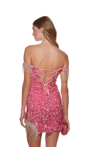 A show-stopping short formal dress made from a bubblegum pink-colored plush sequin fabric with sparkly fringe trim at the sleeves and left hemline. The dress has an off-the-shoulder neckline and a lace-up back style for a custom fit.