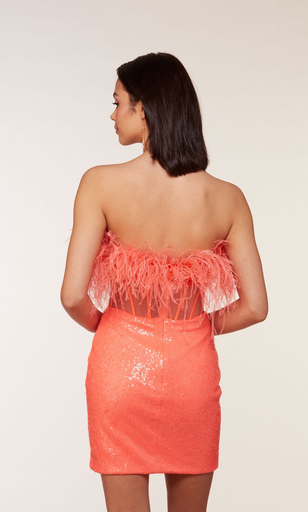 A chic, feather dress with a strapless corset bodice with a zip-up back and fitted sequin skirt in hot coral.