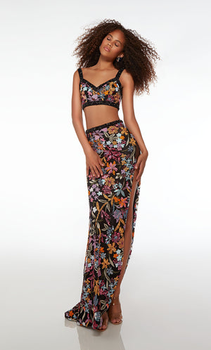 Chic black two-piece dress: V-neck crop top and high-waisted skirt adorned with black rhinestone trim, high slit, slight train, and colorful sequined flowers.